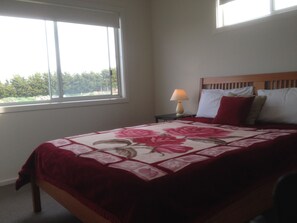 Enjoy a restful stay in this cozy room with a single bed, nightstand, and window offering a view of lush greenery.