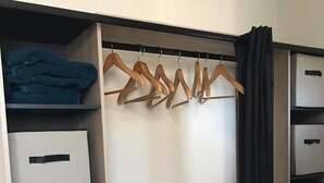Un dressing avec de nombreuses étagères et un grand espace pour suspendre les vêtements, équipé de cintres en bois et de boîtes de rangement.
