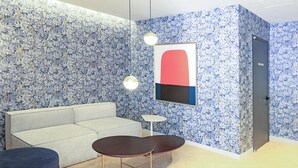 Un intérieur moderne avec un mur orné de motifs, un canapé, une table ronde et des luminaires suspendus.
