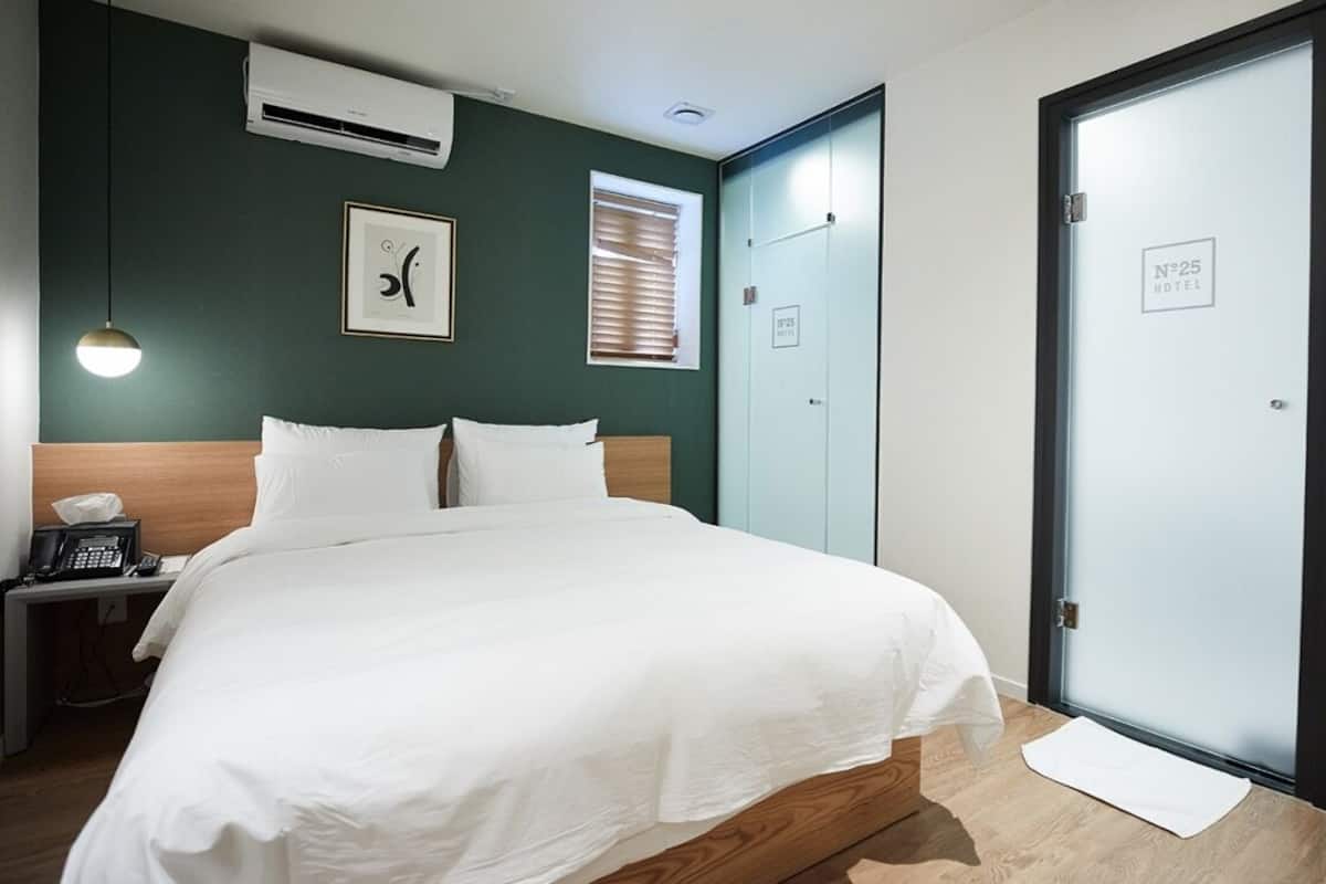 Une chambre d’hôtel avec un lit, une table de chevet, un téléphone et une porte avec une pancarte.