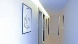 Un couloir aux murs ornés de tableaux encadrés, avec des portes donnant sur différentes pièces et un sol recouvert de moquette.