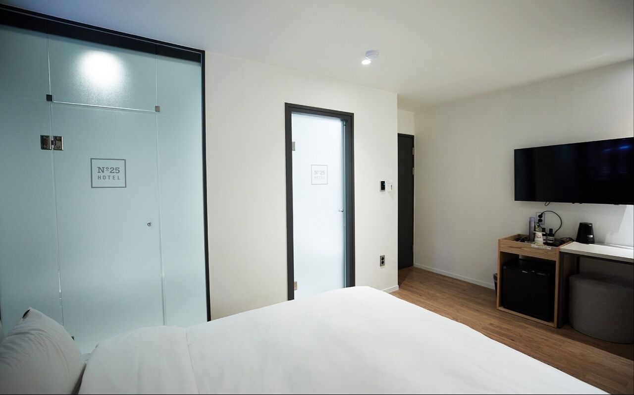 A hotel room with a bed, a TV, a desk with a coffee machine, and a wardrobe.