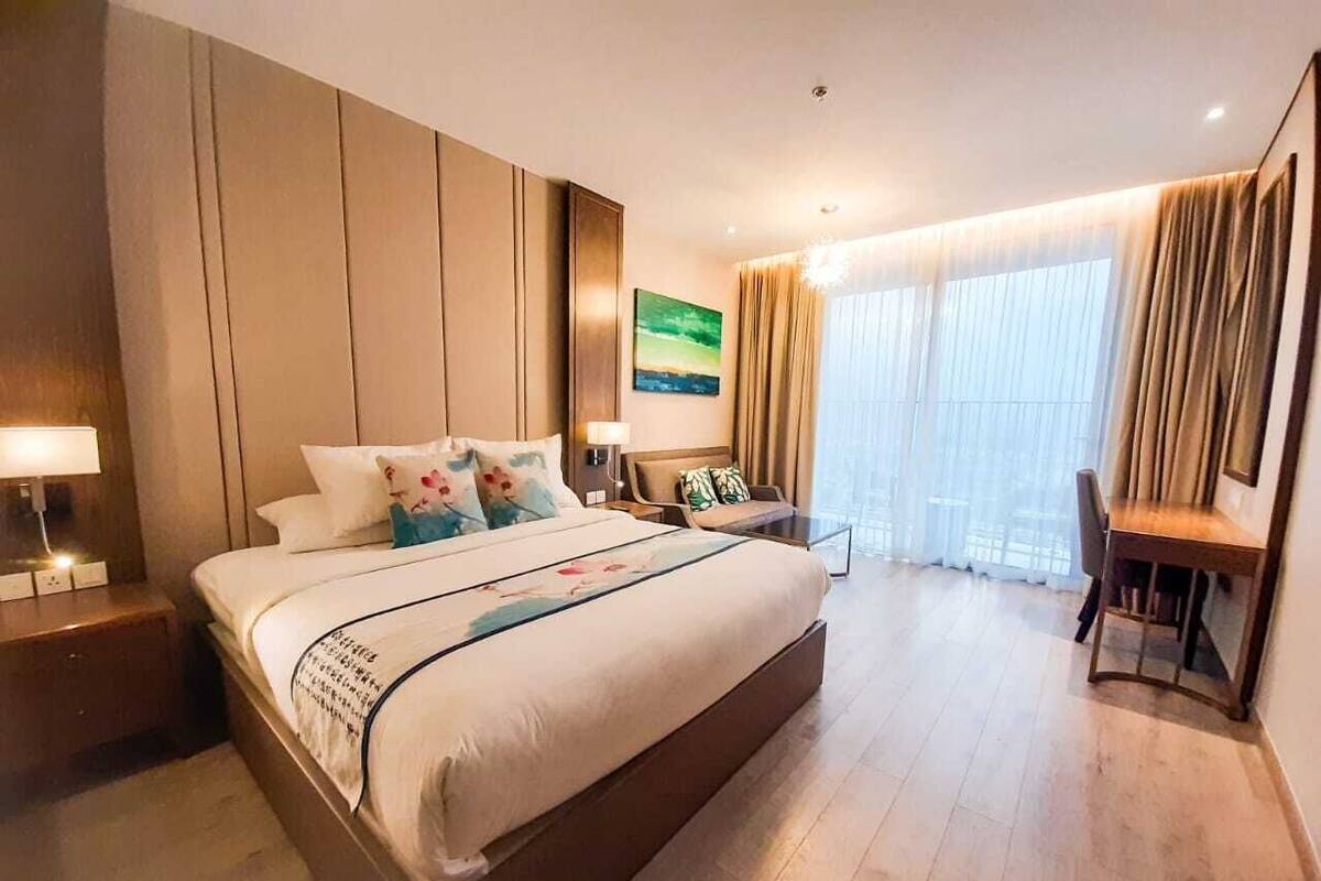 A spacious hotel room with a large bed, a desk, and a chair.