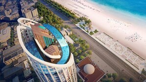 A high-rise building with a curved design, a rooftop pool, and a beach view. - Cala Coastline Panorama (Nha Trang)