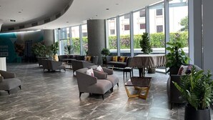 A spacious lobby with modern furniture, large windows, and indoor plants. - Cala Coastline Panorama (Nha Trang)