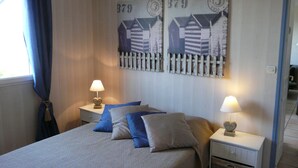 A bedroom with a bed, two nightstands, a lamp, a wall clock, and a window with curtains. - The bay house with heated indoor pool (Saint-Jean-du-Doigt)