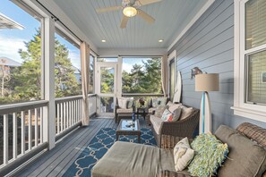 A covered porch with wicker furniture, a ceiling fan, and a surfboard.