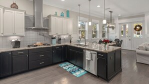 A modern kitchen with dark cabinets, a stainless steel range, and a large island. - Three Times The Fun by AvantStay | Blue Mountain | Pool + Pet-Friendly (Santa Rosa Beach)
