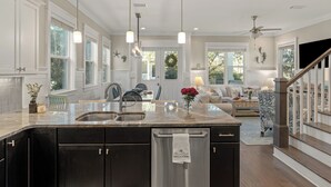 A spacious kitchen with a large island, dark cabinets, and pendant lighting. - Three Times The Fun by AvantStay | Blue Mountain | Pool + Pet-Friendly (Santa Rosa Beach)