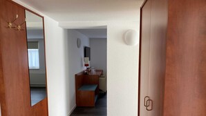 A hallway with wooden doors, a bench, a desk with a lamp, and a mirror.