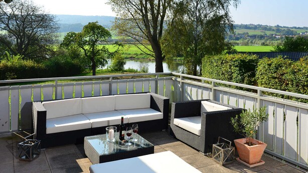 A balcony with a sofa, a table, and a potted plant.
