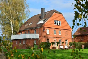 Une maison en briques rouges, avec un toit en pente, une cheminée et un balcon.