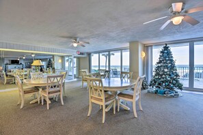 Enjoy meals in this dining area with a round table and six comfortable chairs, surrounded by a high ceiling and a large window offering ocean views.
