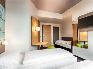 A modern hotel room with a bed, bedside tables, a mirror, and a wall-mounted shelf.