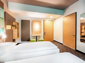 A hotel room with two beds, a wooden door, a mirror, and a wall-mounted shelf. - B&B Hotel Stuttgart-Neckarhafen (Stuttgart)