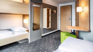 A modern hotel room with a bunk bed, a bedside table, a mirror, and a small green stool. - B&B Hotel Stuttgart-Neckarhafen (Stuttgart)