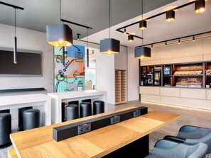 A modern bar area with a wooden counter, black stools, and pendant lighting. - B&B Hotel Stuttgart-Neckarhafen (Stuttgart)