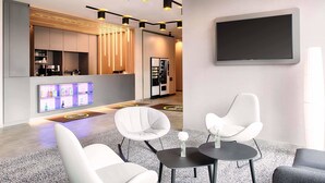 A modern hotel lobby with a reception desk, seating area, and a large TV screen. - B&B Hotel Stuttgart-Neckarhafen (Stuttgart)