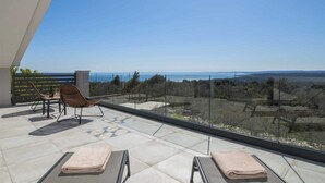 A balcony with a clear view of the sea, a chair, and a table with a bottle. - Villa A.R.T. Viskovici (Koromačno)