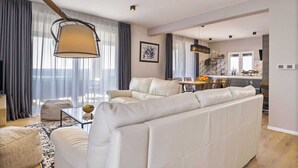 A modern living room with a sofa, a dining area, and a kitchen. - Villa A.R.T. Viskovici (Koromačno)