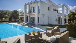 Ein modernes, zweistöckiges Haus mit Swimmingpool, Sitzgelegenheiten im Freien und einer Pergola.