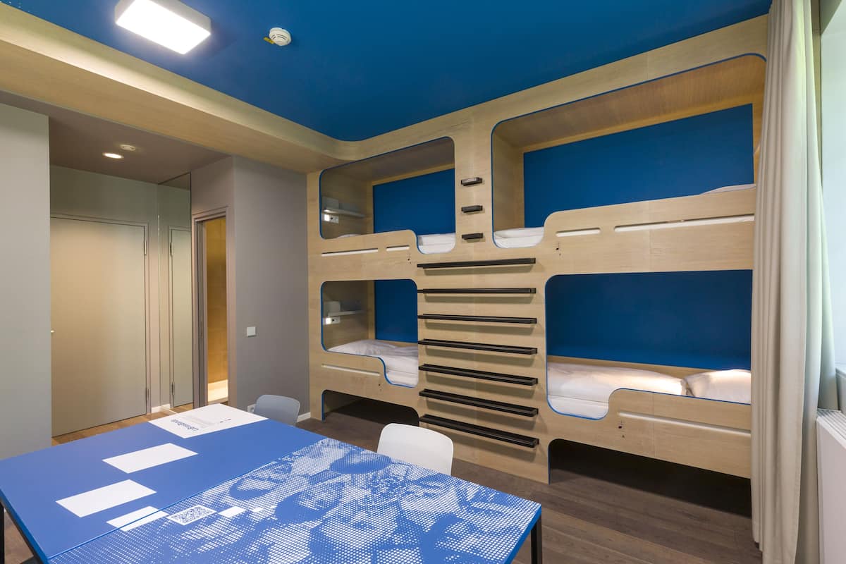 A room with bunk beds, a table, and a chair.