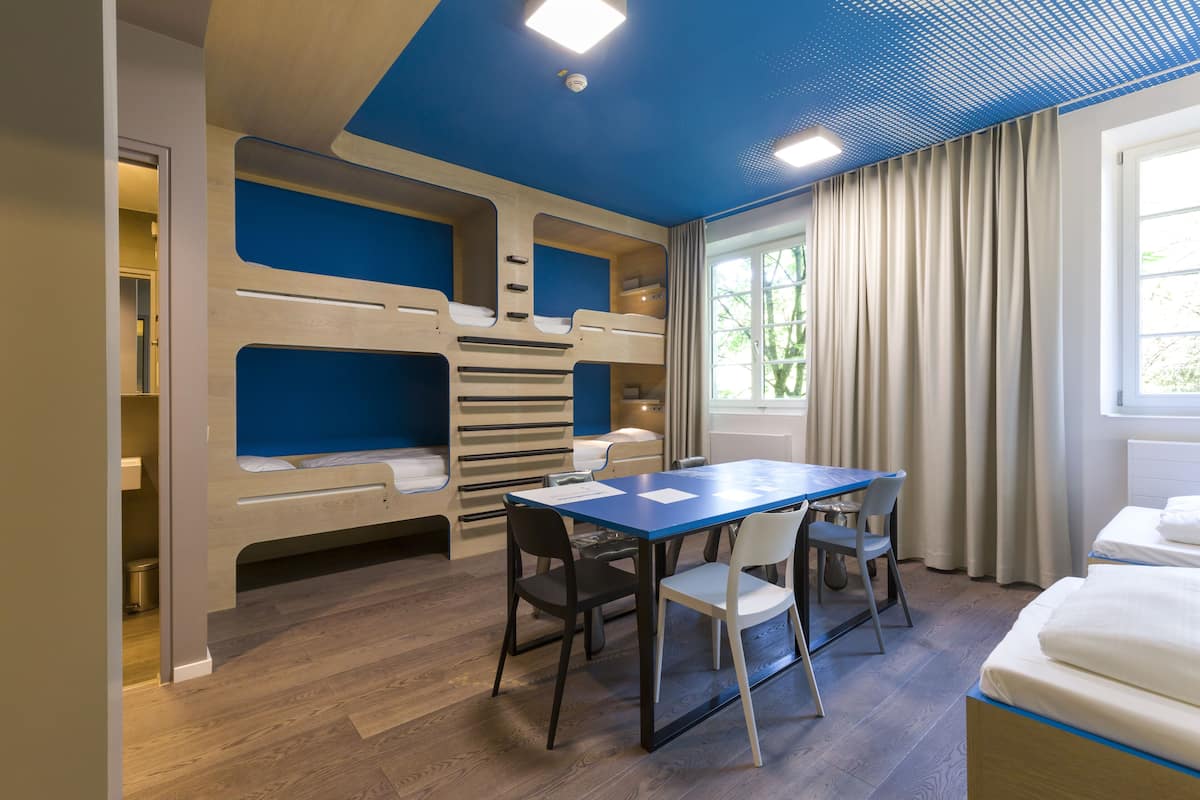 A modern room with bunk beds, a dining table, and chairs.