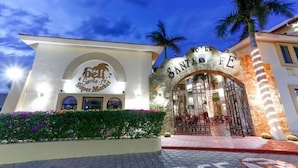 Ein Hotel Eingang mit einem steinernen Bogen, einem Schild mit der Aufschrift 'Hotel Santa Fe' und einer Palme im Hintergrund.
