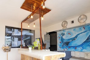 A reception area with a wooden ceiling, hanging light fixtures, a reception desk, a large wall mural of a whale, and two wall clocks.