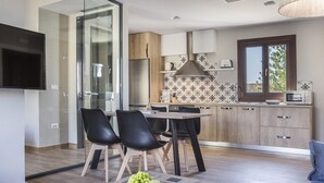 Eine moderne Küche mit Essbereich, einem an der Wand befestigten Fernseher und einem großen Fenster.