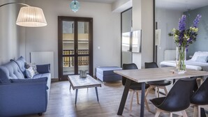 Ein modernes Wohnzimmer mit Sofa, Couchtisch und Esstisch. Ein großes Fenster bietet Blick ins Freie.