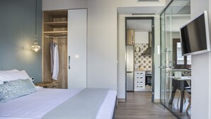 Ein modernes Schlafzimmer mit einem großen Bett, einem begehbaren Kleiderschrank und einer Küchenzeile im Hintergrund.