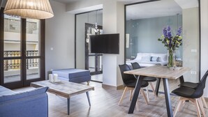 Ein modernes Wohnzimmer mit Couchtisch aus Holz, blauem Sofa und Essbereich mit Holztisch und schwarzen Stühlen.