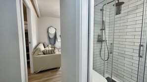 A modern bathroom with a glass shower enclosure, a towel rack, and a visible showerhead.