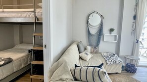 A bunk bed, a sofa with pillows, a round mirror, a small plant, and a window with curtains. - ROCAMAURA IV 3-12 (Estartit)