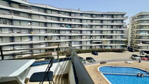 A multi-story hotel with balconies, a swimming pool, and a parking area.
