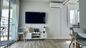 A modern living room with a flat-screen TV, a white cabinet, a desk, and a chair. - ROCAMAURA IV 3-12 (Estartit)