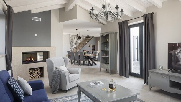 A modern living room with a fireplace, a dining area, and a staircase leading to an upper level.