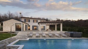 A modern two-story house with a swimming pool, outdoor seating, and a hot tub.
