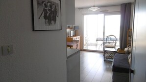 A spacious living area with a dining table, chairs, a sofa, and a large window with a view. - Charming 30m² 2-room, south loggia, parking in Sète, sea view (Sète)