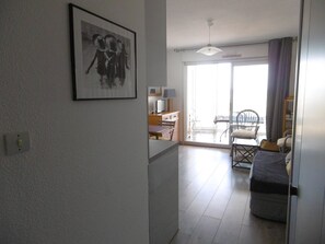 A spacious living area with a dining table, chairs, a sofa, and a large window with a view.