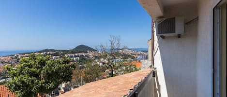 Un balcón con vista a una ciudad costera, incluyendo una montaña y una masa de agua.
