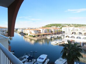 A marina with boats docked, a clear sky, and buildings with red-tiled roofs.