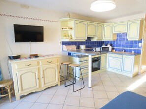 A compact kitchen with a flat-screen TV, a microwave, and a toaster.