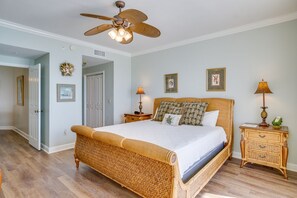 A spacious bedroom with a large bed, a ceiling fan, and a nightstand with a lamp.