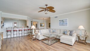 A spacious living room with a large sectional sofa, a dining area with bar stools, and a ceiling fan. - Grand Surf 7W! PCB Most Prestigious Address. Huge Condo, Exceptional. (Panama City Beach)