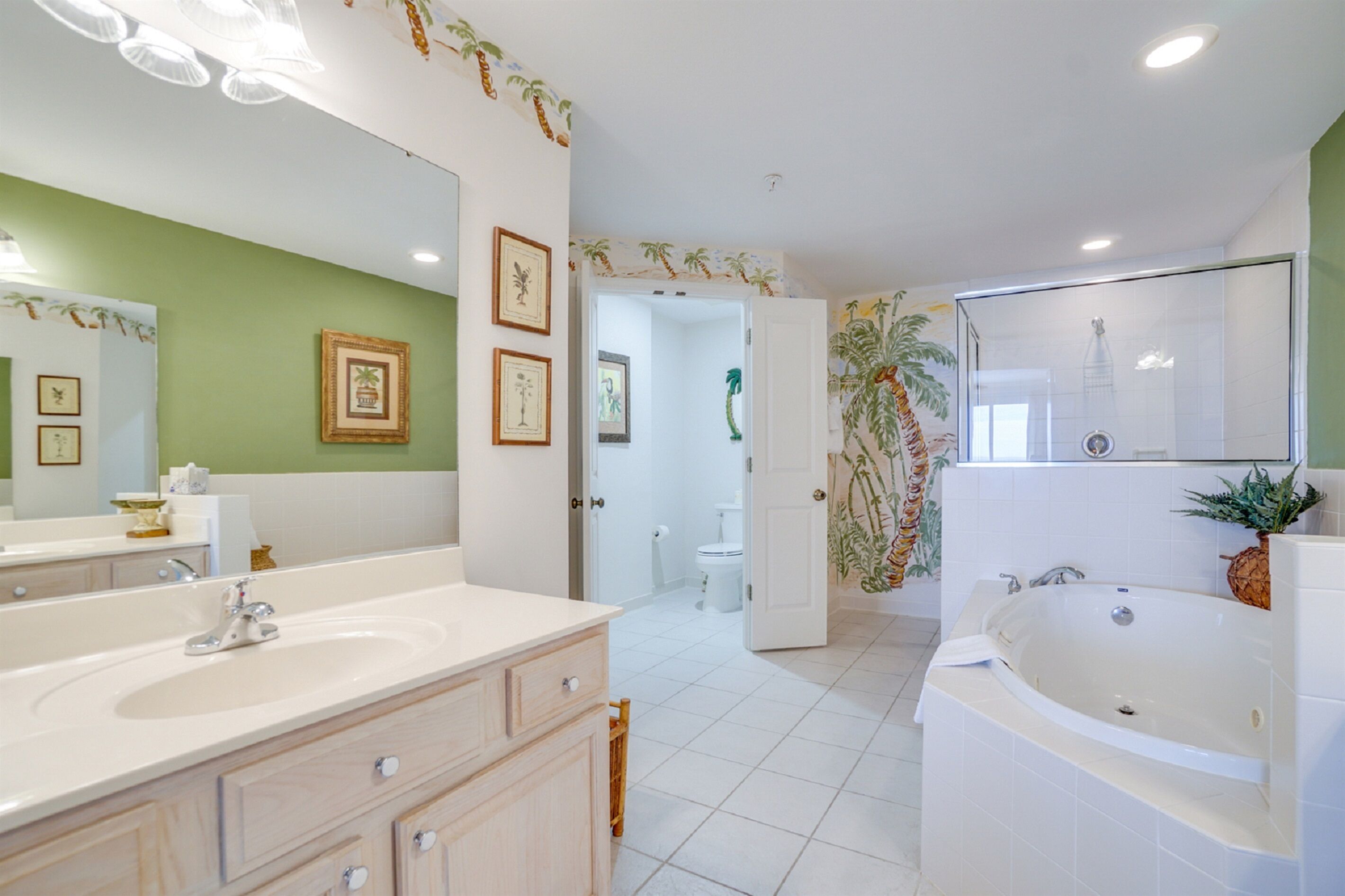 A bathroom with a large mirror, two sinks, a bathtub, and a toilet.