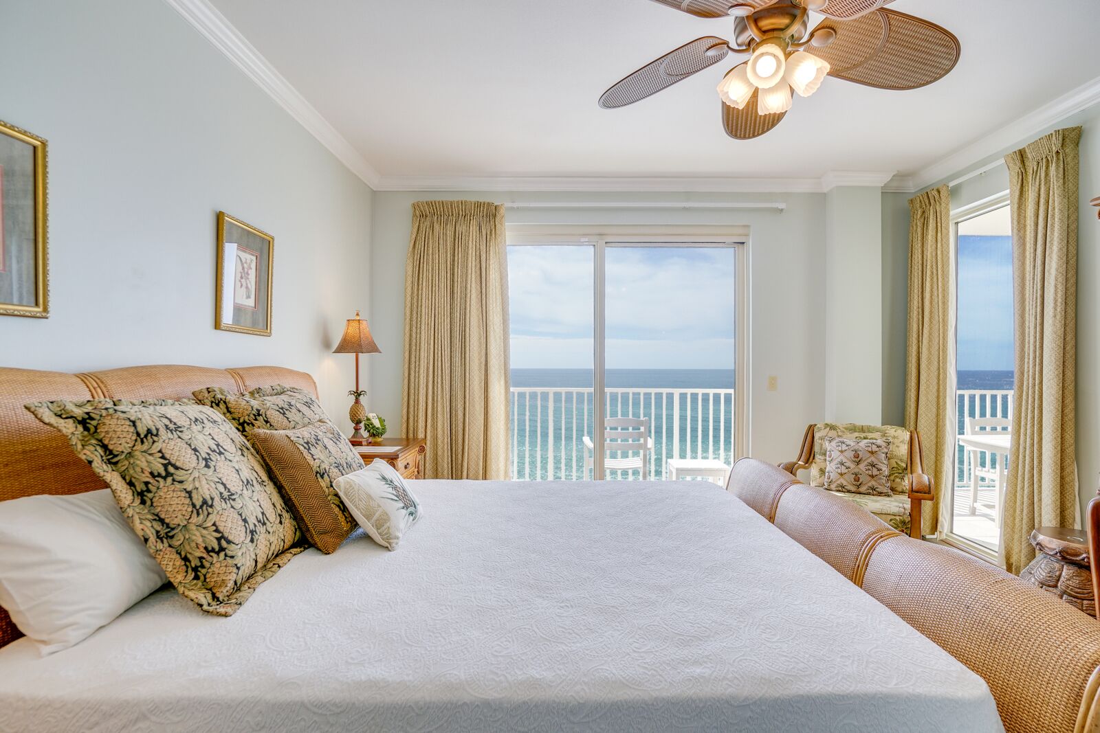 Ein geräumiges Schlafzimmer mit einem großen Bett, einem Deckenventilator und einem Balkon mit Meerblick.