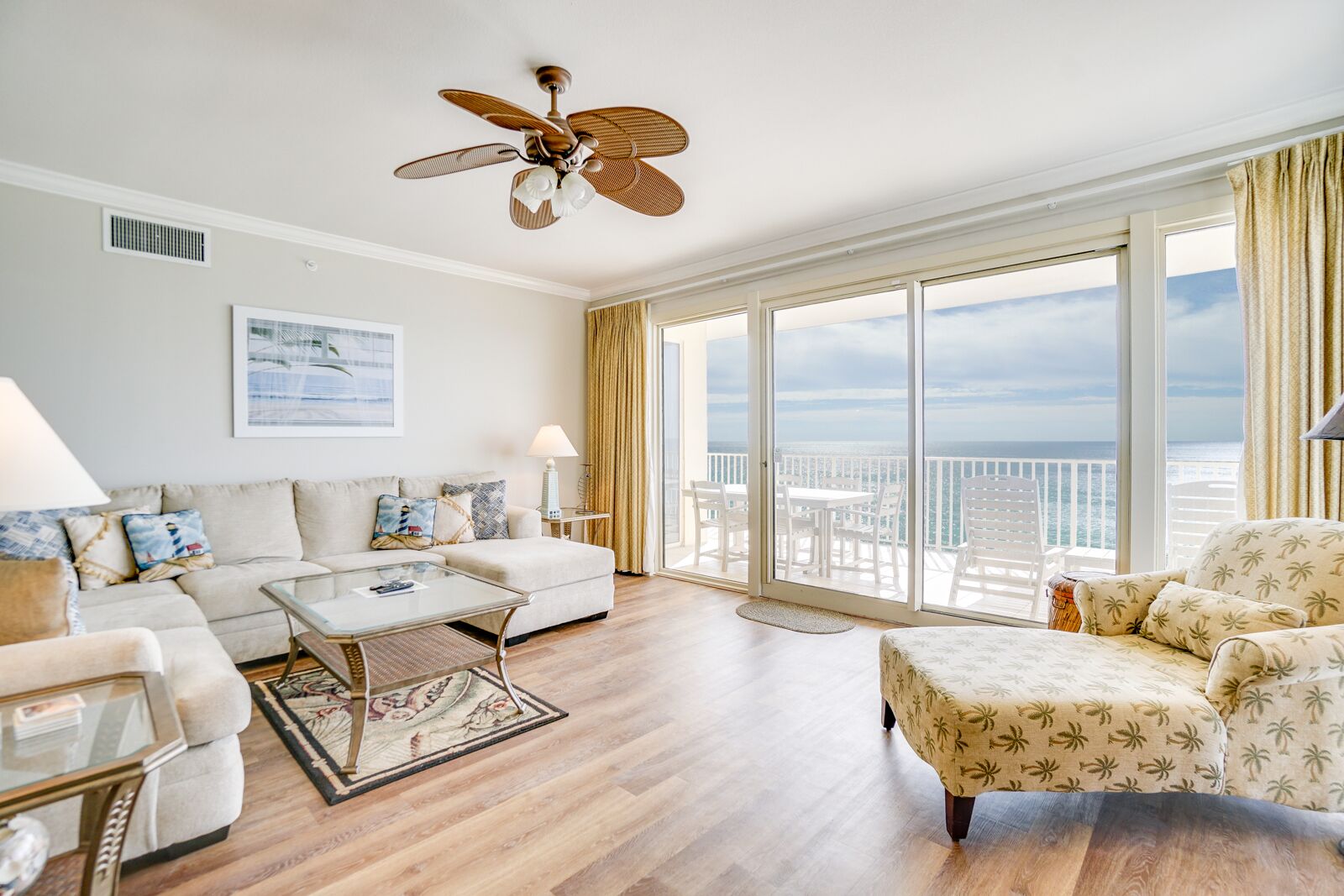 A spacious living room with a large window, a ceiling fan, and a view of the ocean.
