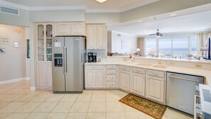 A modern kitchen with a built-in refrigerator, a coffee maker, and a view of the city through the window. - Grand Surf 7W! PCB Most Prestigious Address. Huge Condo, Exceptional. (Panama City Beach)